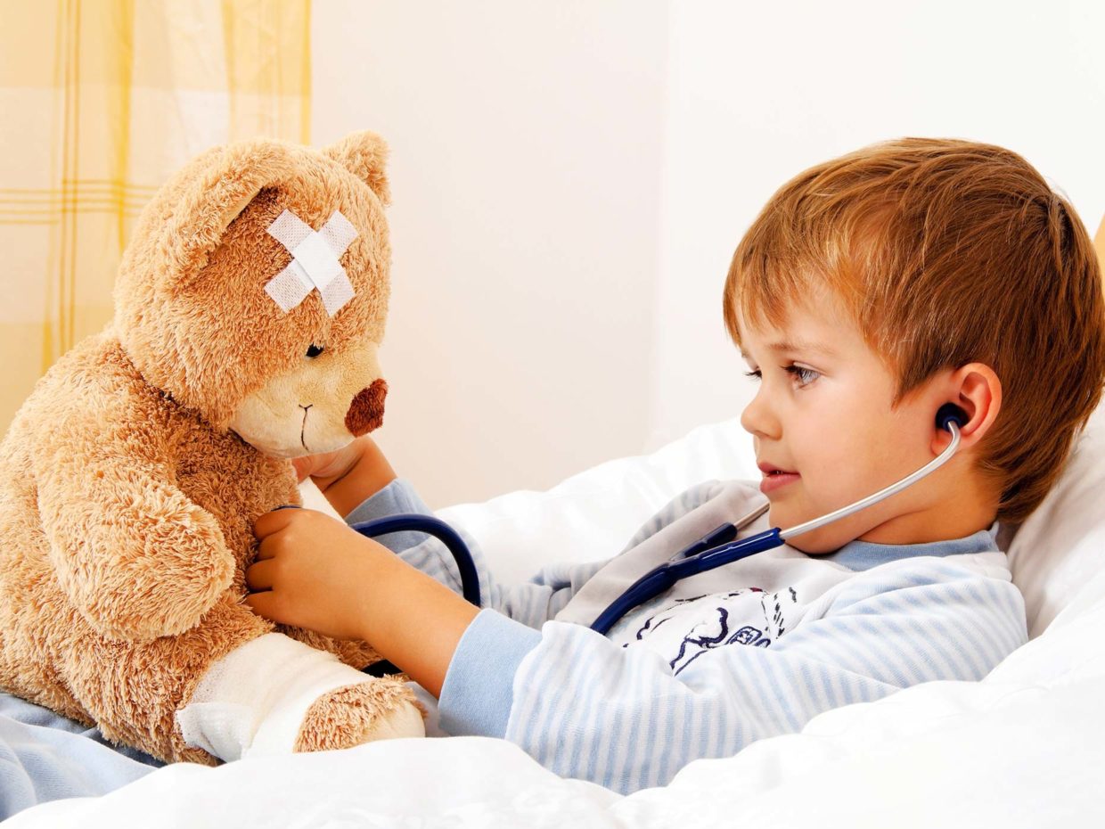 bambino a letto gioca facendo finta di visitare il suo orsacchiotto malato