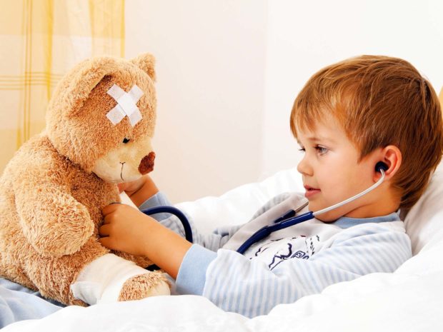 bambino a letto gioca facendo finta di visitare il suo orsacchiotto malato