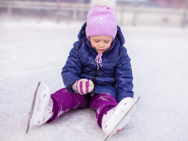 bambino appena caduto sulla pista di pattinaggio sul ghiaccio