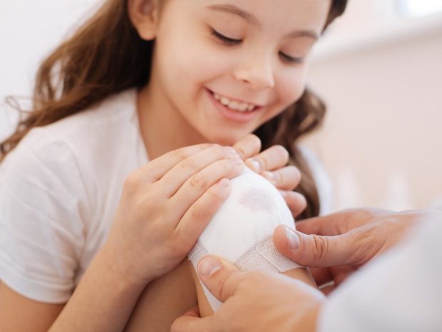 adulto applica garza sterile sul ginocchio di una bambina