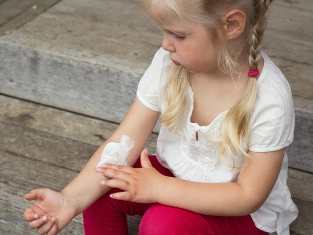 bambina bionda spalma crema sul suo braccio