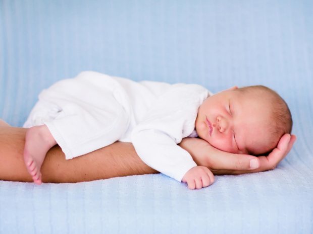 neonato dorme sul braccio di un adulto