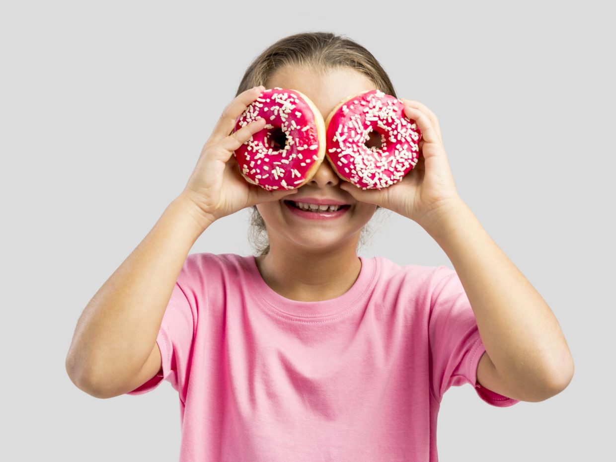 bambina gioca con le ciambelle usandole come occhiali