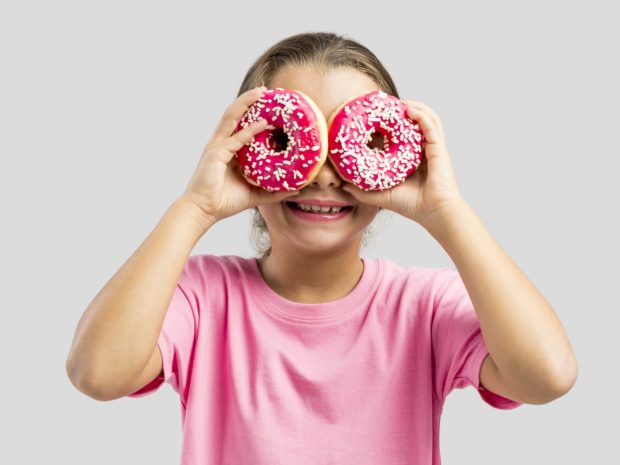 bambina gioca con le ciambelle usandole come occhiali