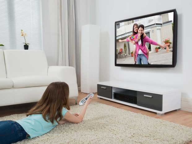 bambina distesa per terra guarda la televisione
