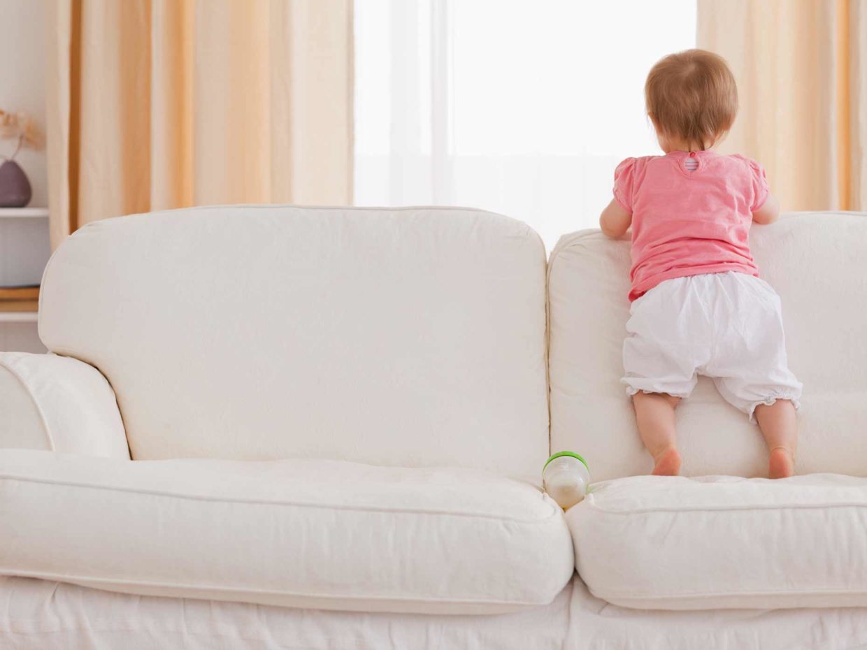 bambina piccola in piedi sopra il divano