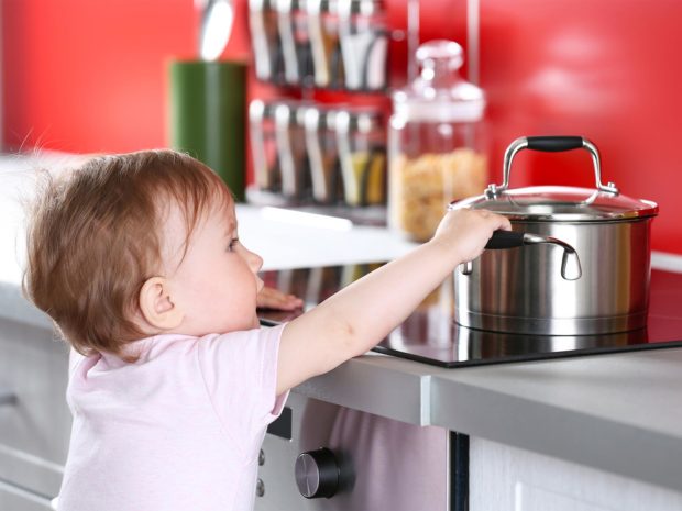 bambino prova a prendere il pentolino dal piano cottura