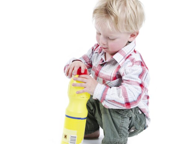 bambino gioca con una bottiglia di liquido velenoso