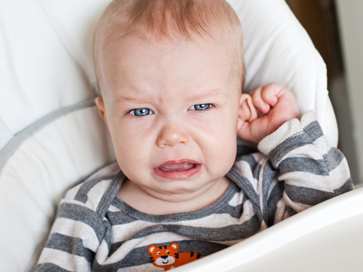 bambino piccolo piange toccandosi l'orecchio