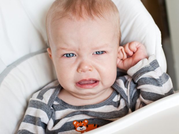 bambino piccolo piange toccandosi l'orecchio