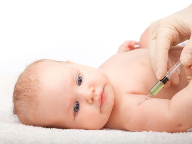 neonato guarda preoccupato la siringa vicino la sua spalla