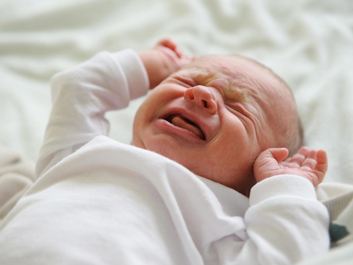 neonato disteso sul letto piange