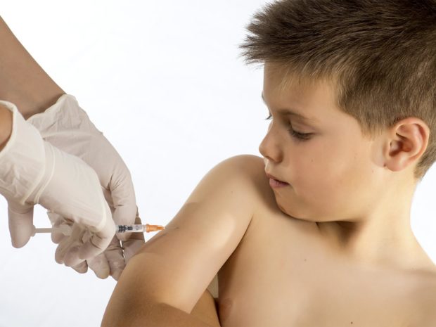 ragazzino guarda la siringa usata dal pediatra