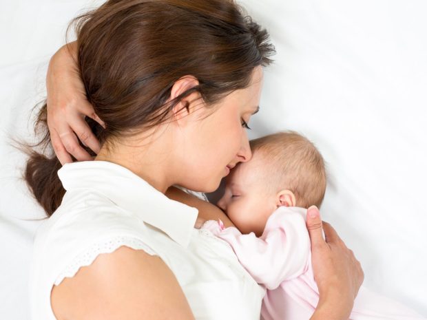 mamma abbraccia nel letto il suo neonato