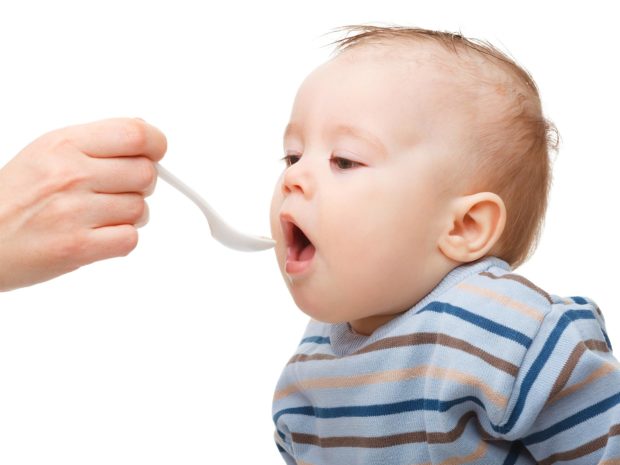 bambino piccolo viene imboccato con il cucchiaino