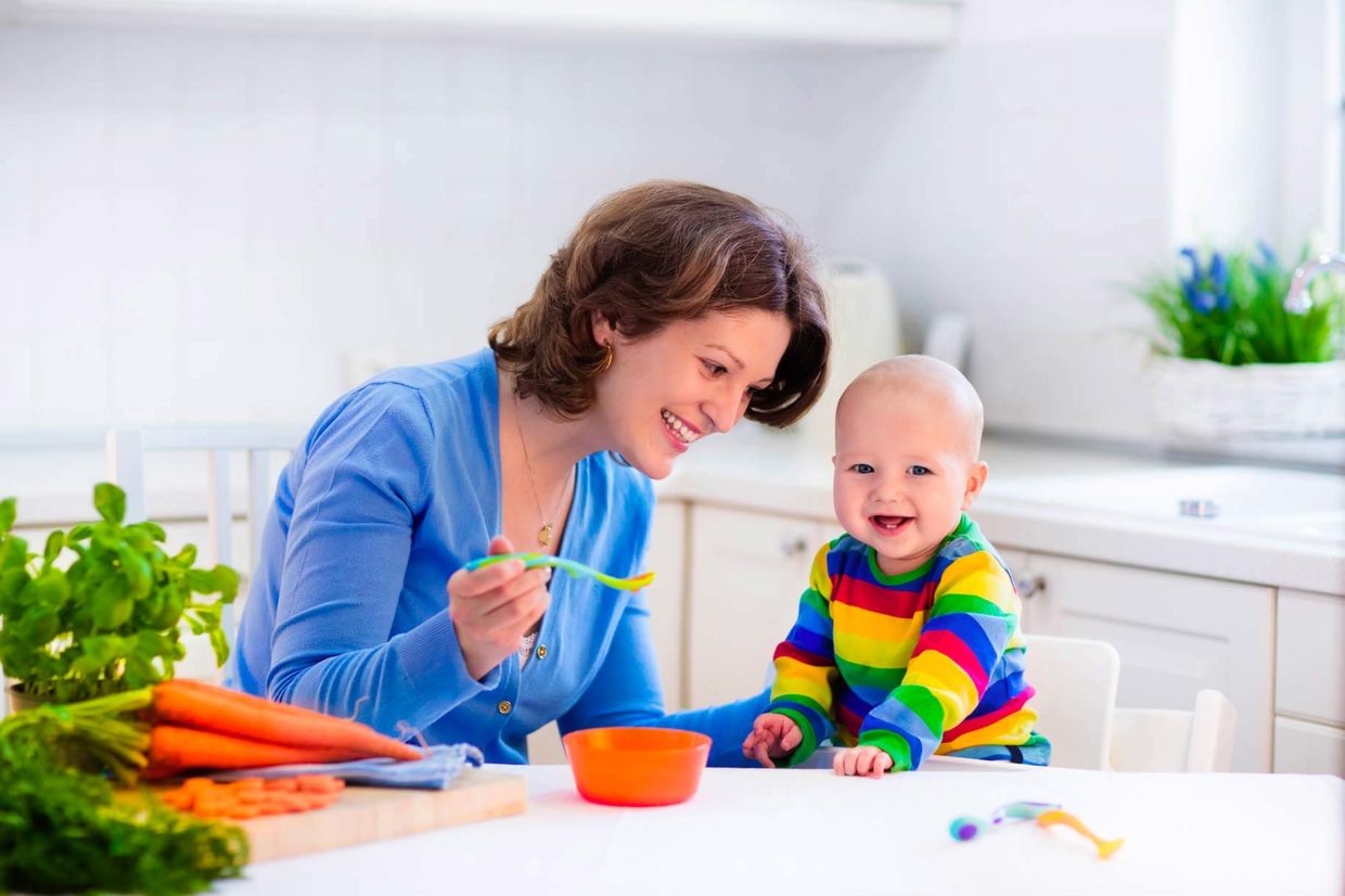 mamma dà da mangiare al figlio piccolo con il cucchiaino