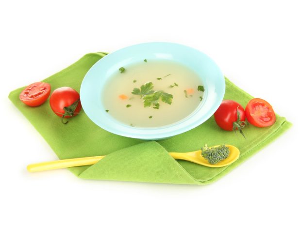 piatto di brodo vegetale con cucchiaio a fianco