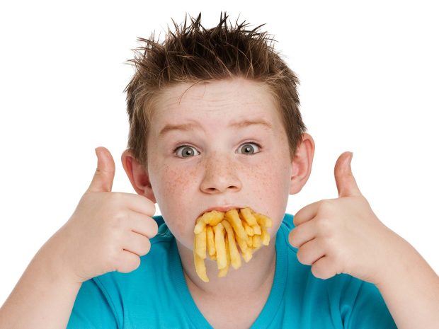 bambino con la bocca piena di cibo spazzatura