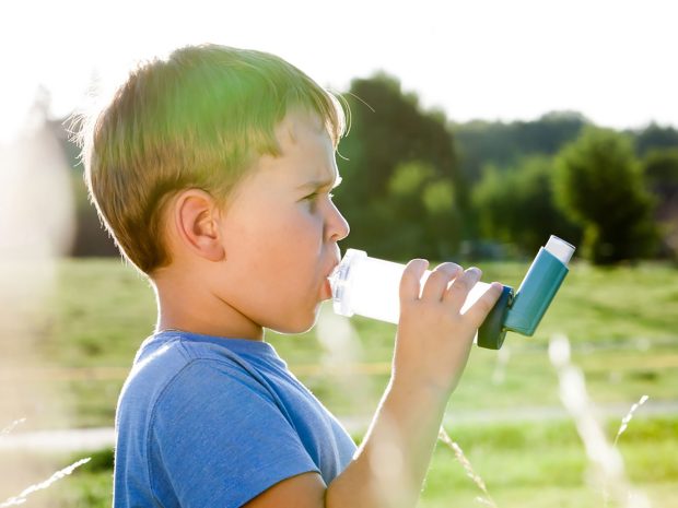 bambino in mezzo al prato utilizza distanziatore per inalatore spray