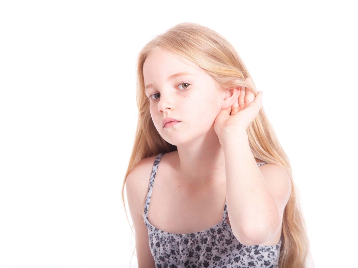 bambina bionda avvicina la mano all'orecchio per ascoltare