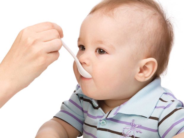 bambino imboccato dal genitore con il cucchiaino