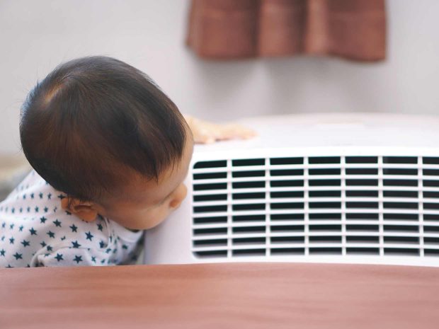 bambino piccolo si appoggia e guarda il condizionatore