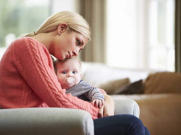 mamma triste abbraccia neonato seduta sul divano