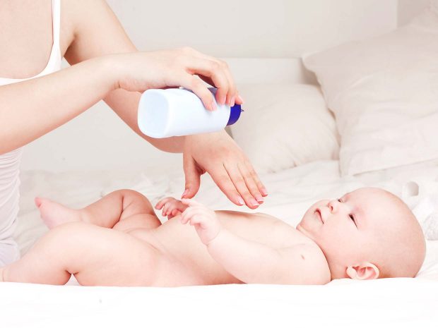 una mamma mette polvere di talco al neonato