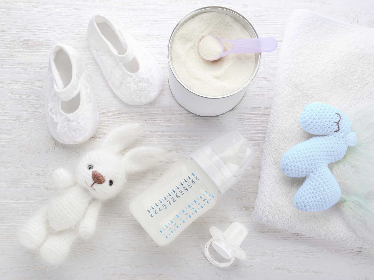 scarpine latte in polvere biberon ciuccio e peluche riposo su un tavolo bianco