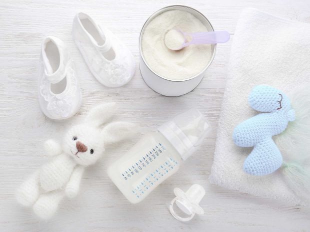 scarpine latte in polvere biberon ciuccio e peluche riposo su un tavolo bianco