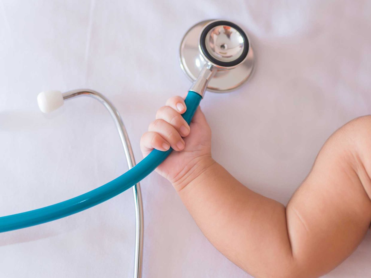 mano di neonato stringe stetoscopio di colore blu