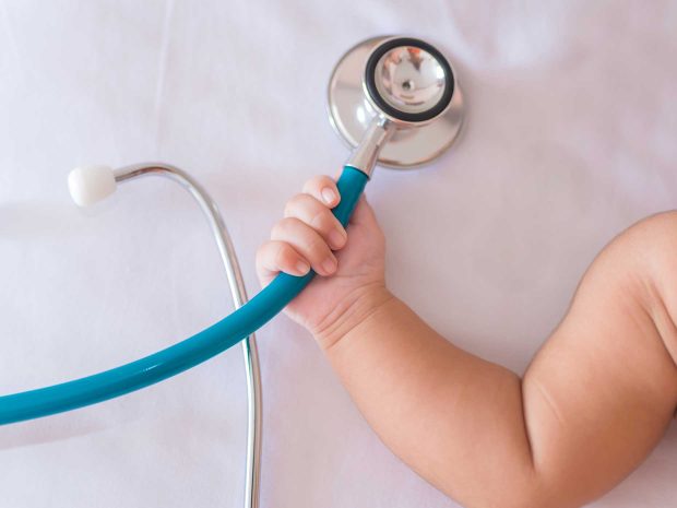 mano di neonato stringe stetoscopio di colore blu