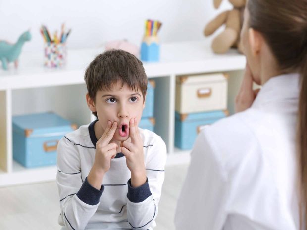 bambino svolge esercizi di logopedia schiacciando le guance con le dita