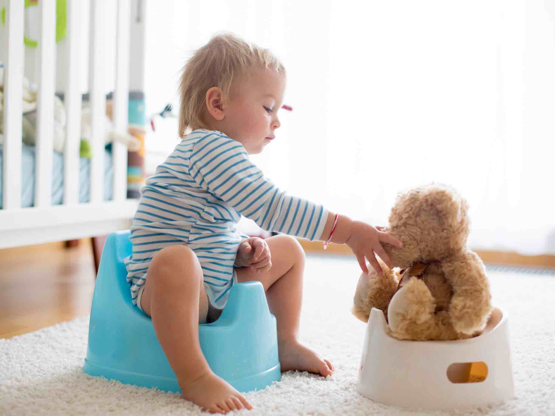 Cute toddler boy, potty training, playing with his teddy bear