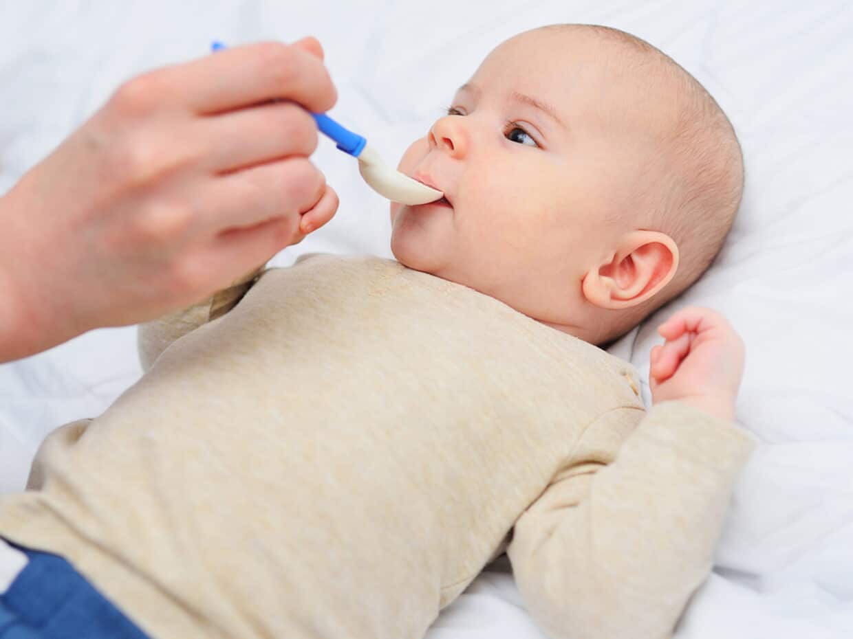 Mamma che dà la soluzione reidratante orale al bambino con un cucchiaino