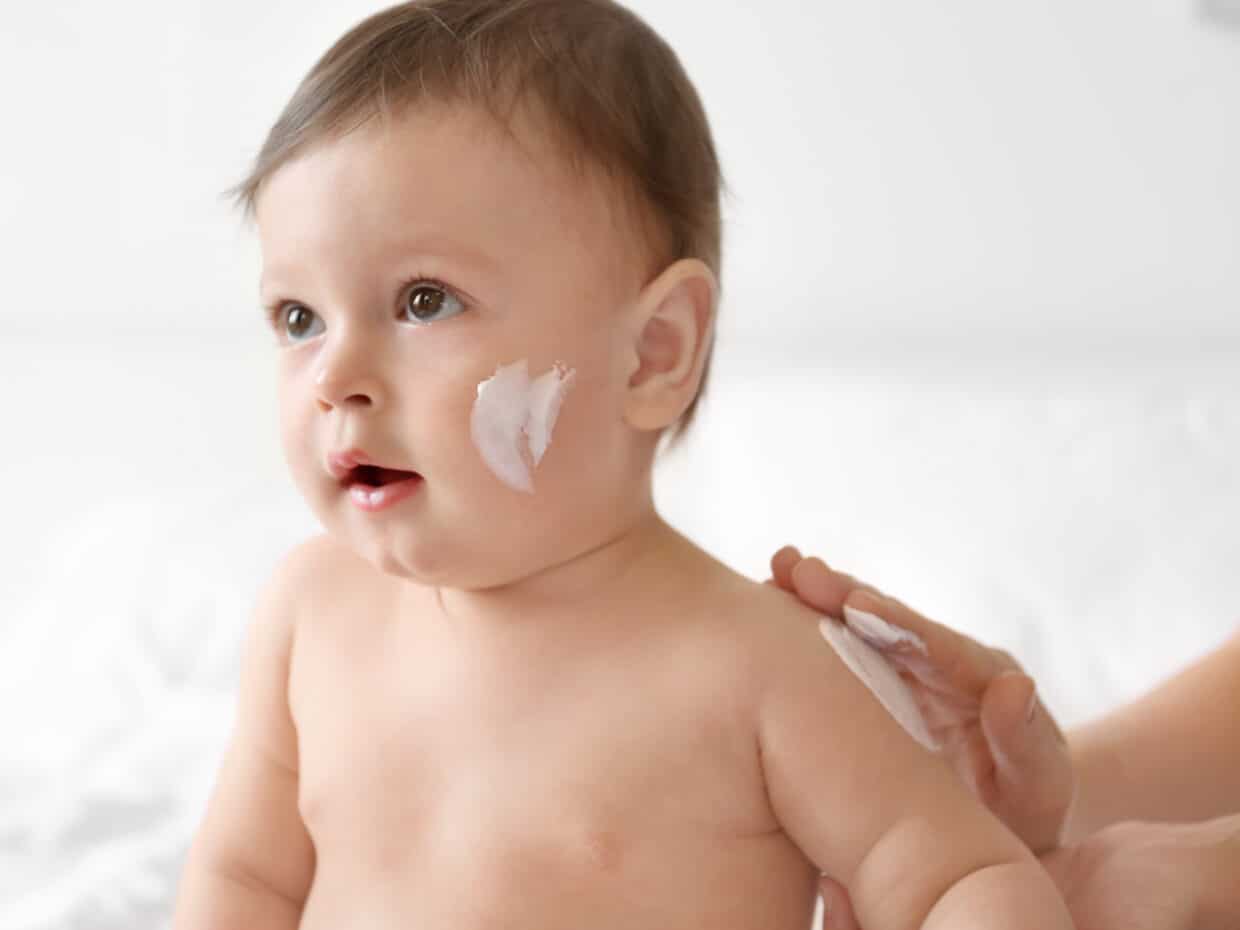 Mamma applica una crema idratante per la pelle secca del bambino