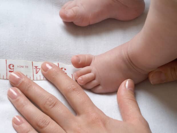 Mamma che misure il piede del bambino per scegliere la misura di scarpe