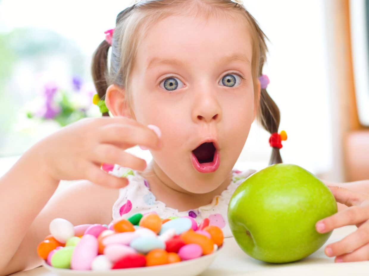 Bambina con dolciumi e frutta