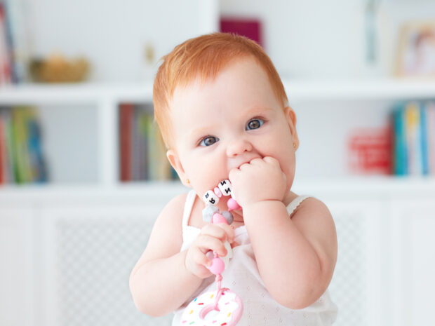 Bambina che mette in bocca la manina come esempio di sintomo della dentizione