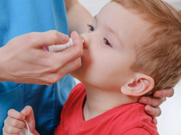 Bambino che riceve dal pediatra il vaccino nasale contro l'influenza