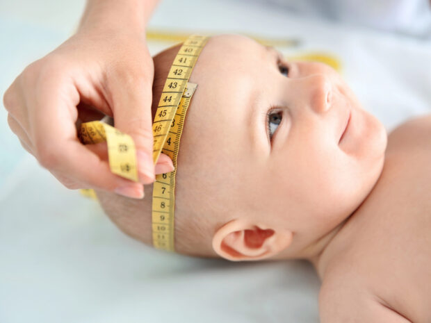 Pediatra misura la circonferenza cranica di un neonato