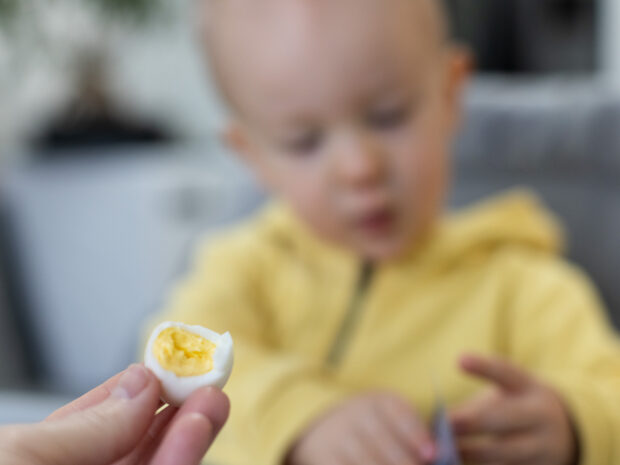 Mamma che offre un uovo sodo al bambino durante lo svezzamento