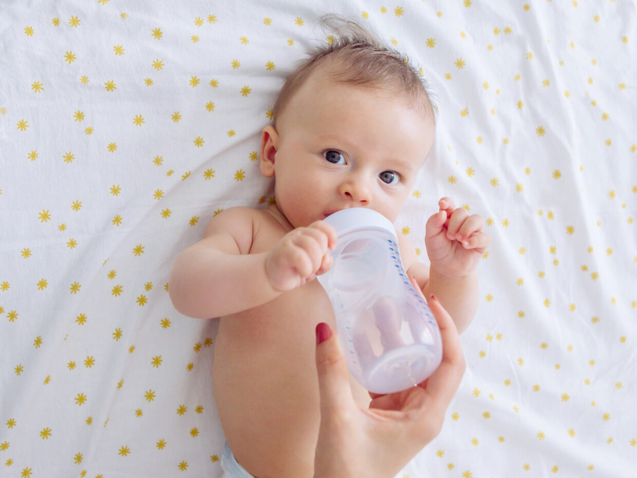 Mamma dà un biberon d'acqua al bambino